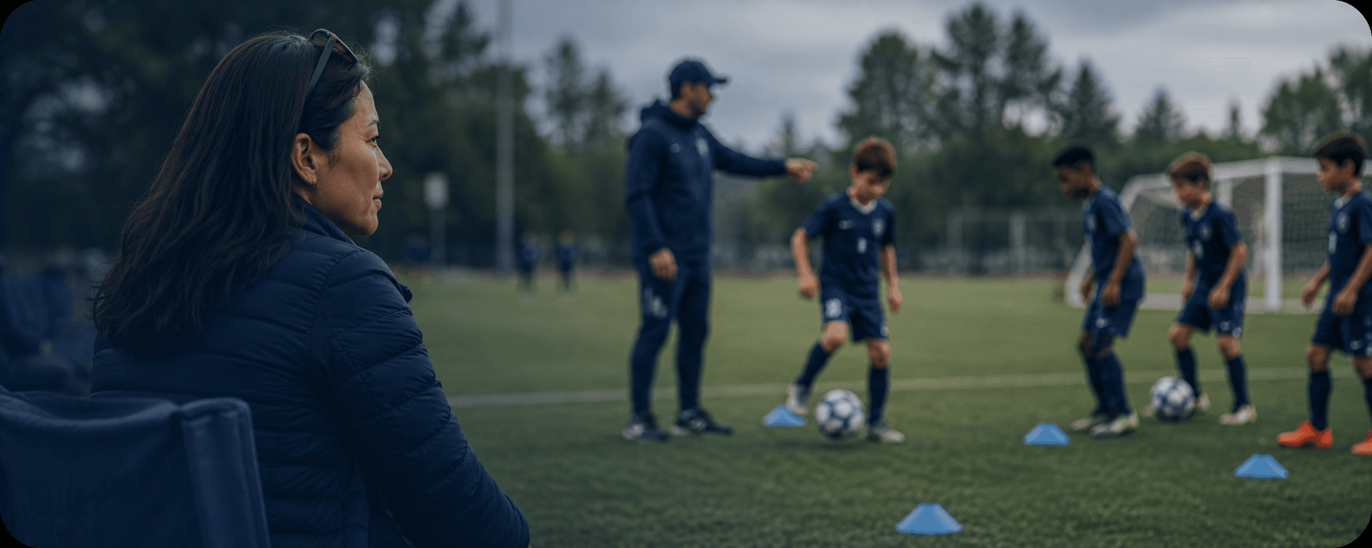 Parent observing from the sideline while players train in the background